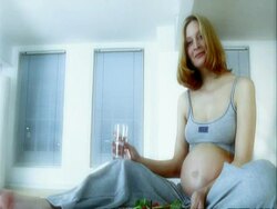CU pan across pregnant woman sitting on bed stoking stomach Stock Footage