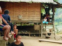 MS SLO MO Shot of children sitting and primitive looking houses / Muang Ngoi, Luang Prabang, Laos Stock Footage