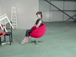 Young woman on swivel chair with pile of chairs Stock Footage