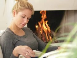 Female in front of fireplace reading book Stock Footage