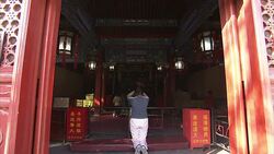 A worshiper enters the Bai Yun Guan Temple, kneels and genuflects. Stock Footage