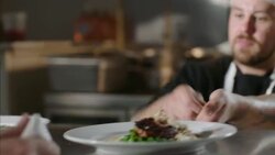 Chef places finished entr_es on ready counter and waiter picks them up for table service in restaurant kitchen Stock Footage