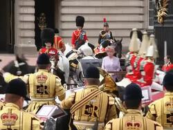 The Monarch Queen Elizabeth reviews her Guards on her Official Birthday, as they march and ride past her as she stands outside at Buckingham Palace in London. Stock Footage