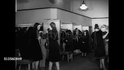 1947: SMALL TOWN DRESS SHOPS: WS Small town street pedestrians traffic shops. INT WS Women shopping in dress store. VS Woman trying on floral print dress. MS Woman looking at gowns dresses w/ saleswoman. New York Instructional Video
