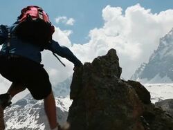 PAN of teenage hiker ascending to pinnacle summit Stock Footage