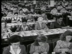 B/W 1944 high angle multiracial workers looking thru boxes for issuance of War Bonds / World War II / news. Stock Footage