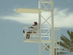 High Speed Tilt down to lifeguard sitting in high chair, Spain. (Individual frames may also be used as a still image. Each frame in its raw state is about 6MB or about 12MB as a 16 bit TIFF) Stock Footage