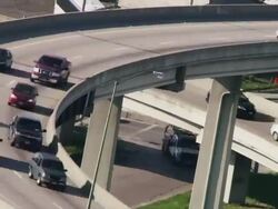 Time lapse overhead shot, cars race around curve and under bridge during commuter traffic congestion on interstate highway. Stock Footage