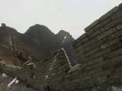 A beautiful section of the Great Wall of China. A steep, deteriorating, snow-covered path leads up to a tower that rests on jagged rocks and mountains. Stock Footage