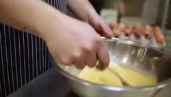 Chef whisking eggs in bowl in commercial kitchen Stock Footage