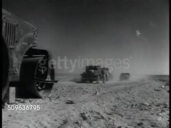 1941: NORTH AFRICA: PAN Captured Italian trucks. Captured Italian General Headquarters tent, sand, wind, flag on top of tent. Trucks moving on desert road, passing Bardia sign. PAN Hundreds of Italian prisoners (POWs) standing together. WWII Instructional Video