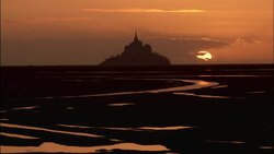 A low sun silhouettes Mt. Saint Michel in Normandy, France. Stock Footage