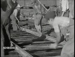 1943: U.S. RAILWAY MISSION IN MEXICO: VS American instructing Mexican workers on rail road track. VS Mexicans hammering, working on. CU Wooden beam being pulled into place under tracks. VS Train dumping gravel. VS Diesel trains passing on tracks. Instructional Video