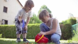 Little boy and toddler girl playing in the garden Stock Footage