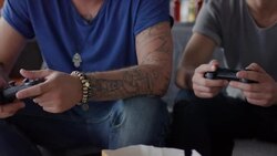 Guys sitting on couch playing video games and cheering Stock Footage