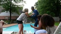 MS Laughing group of friends watching woman try to push friend into pool during backyard party Stock Footage