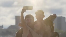 Group of friends pose for selfie overlooking city skyline in slow motion Stock Footage