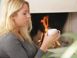 Female in front of fireplace drinking warm tea Stock Footage