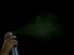 High Speed Aerosol, hand holding can, sprays fine white mist into air against black background Stock Footage