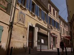 A woman passes a store with a closed storefront gate in Salon-de-Provence, France. Stock Footage