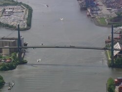 WS AERIAL View of running vehicles of suspension bridge and dockyard near river with running boats / Germany Stock Footage