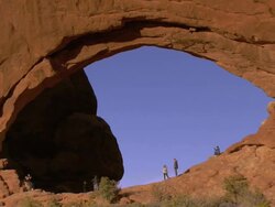 Many people standing within a massive sandstone arch called North Window in the spectacles area Stock Footage