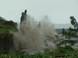 Men on shoreline as waves crash into it, Philippines, Typhoon Mirinae 2009 Stock Footage