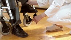 DS doctor helping elderly patient to walk away from wheelchair Stock Footage