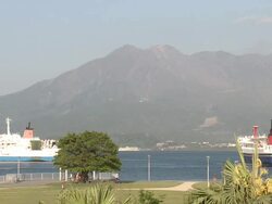 Ship manouvres in Kagoshima port with Sakurajima volcano in the background, Japan Stock Footage