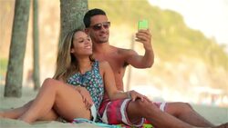 Young Brazilian couple snap goofy smartphone photos on Rio beach Stock Footage