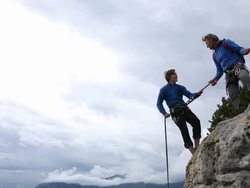 Father instructs son while climbing rock cliff Stock Footage