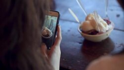 Two young women take photos of ice cream sundae with smartphone Stock Footage