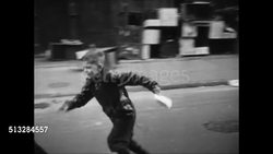 1950: URBAN NEIGHBORHOOD: Boys playing in street, one chasing another skating on roller skates. Children playing on sidewalk. Instructional Video