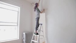Woman on ladder replacing batteries in ceiling smoke detector Stock Footage