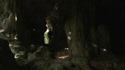 A scientist with a headlamp walks inside a dark cave. Stock Footage