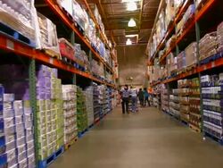 WS POV Aisle with floor to ceiling shelves stacked with household supply items in big box discount store / Palm Desert, California, USA Stock Footage