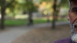 Old street musican in urban park stares at camera Stock Footage