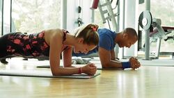 Man and woman in plank position on exercise mats in gym Stock Footage