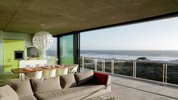 Living room sliding doors open to balcony overlooking ocean Stock Footage