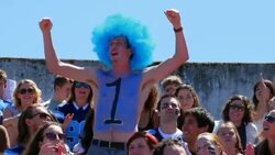 MS Male football fan wearing wig with a number one painted on chest standing in stadium cheering Stock Footage
