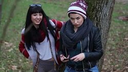 Two funny looking girlfriends posing by a tree in a park on a sunny autumn day Stock Footage