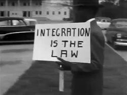 B/W 1950s Black male demonstrator carrying sign - "Integration is the Law" on sidewalk / Texas Stock Footage