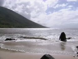 MS Waves rolling gently into shore near vegetation covered mountains / Great Barrier Reef, Australia Stock Footage