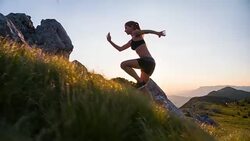 Young female athlete running up the mountain at sunset Stock Footage