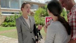 Realtor giving happy couple keys in front of house with Sold sign Stock Footage