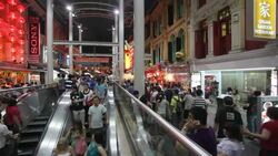 Commuters and shoppers maneuver through the Chinatown Night Market and the MTR subway entrance in Singapore. Stock Footage