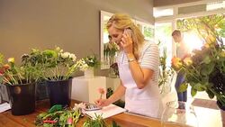 Florist taking order on cell phone in flower shop Stock Footage