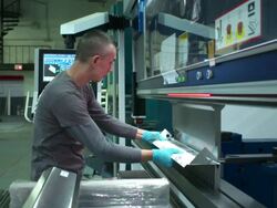 Dolly out on medium profile shot of man bending a piece of metal in a machine. Stock Footage