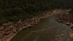 A river snakes past boulders and forested mountains. Stock Footage