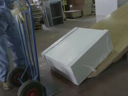 worker in furniture factory, manoeuvring piece of furniture,  loading it on hand truck and moving it to storage area Stock Footage
